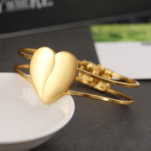 Elegant gold open bangle with a large matte heart charm on a minimalist double band