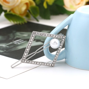 Close-up of geometric silver hair clip with rhinestones and white faux pearl detail