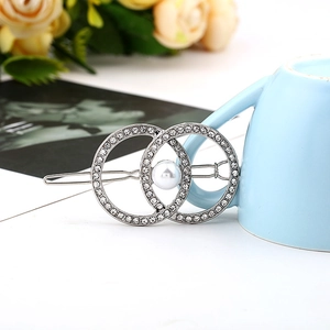 Close-up of interlocking metal rings hair clip with pavé rhinestones and a white faux pearl