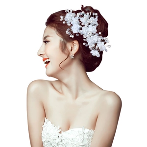 Elegant bridal hair pin with white fabric flowers and pearls on a bride with lace dress