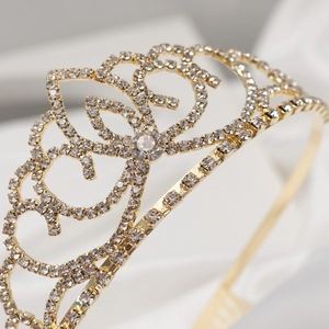 Detailed close-up of golden bridal crown with intricate filigree and clear rhinestones