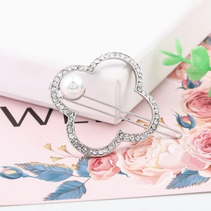 Detail of silver clover hair clip with white rhinestones and a large pearl ornament