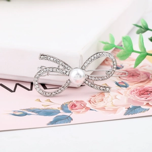 Close-up of silver bow hair clip with white pearls and rhinestones on a spring clip