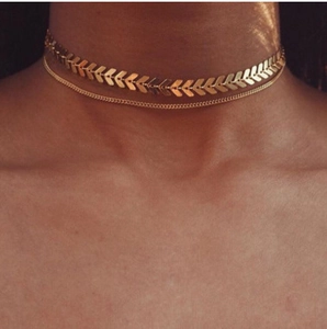 Close-up of a double-layered gold necklace with fishbone sequins and a minimalist link chain