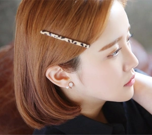 Détail d'une pince à cheveux léopard et de boucles d'oreilles perles sur un modèle