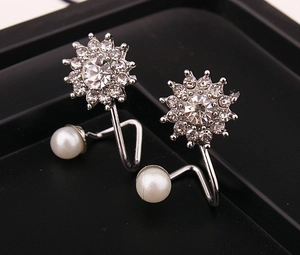 Gros plan de boucles d'oreilles tournesol argentées avec zircons blancs et perles