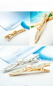 Detail view of alloy leaf hair clips with pearls in gold and silver finishes