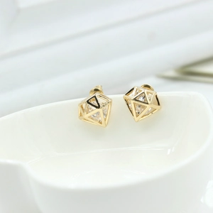 Détail de boucles d'oreilles géométriques dorées avec zircone sur une tasse en céramique blanche