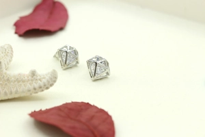 Vue macro de boucles d'oreilles géométriques argentées avec pierre de cristal ronde