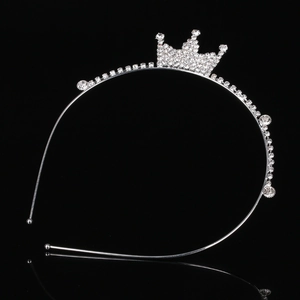 Macro view of silver rhinestone tiara headband with glossy crown detail on black surface