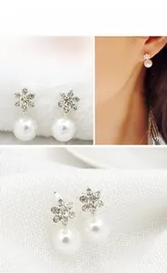 Close-up of snowflake stud earrings featuring rhinestones and white pearls on velvet