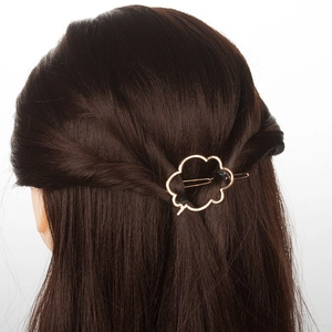 Détail d'une pince à cheveux dorée en forme de nuage sur de longs cheveux bruns