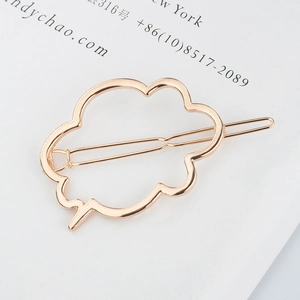 Gros plan d'une pince à cheveux nuage creuse en métal doré rose sur une page blanche