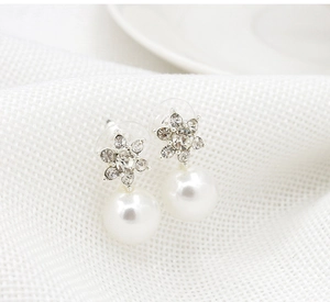 Detailed macro view of silver star stud earrings with rhinestones and large round pearls