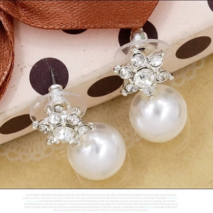 Elegant star-shaped rhinestone earrings with white pearls on a gift box background