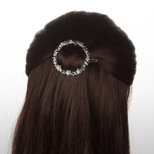 Detail of a silver circular hair clip with small stars worn on dark brown hair