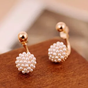 Eleganti orecchini dorati con sfere di perle a grappolo su sfondo di legno rustico