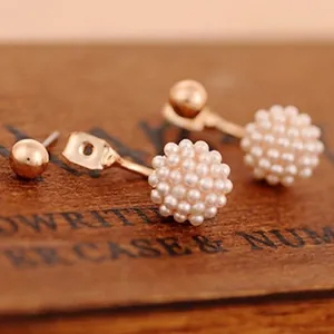 Orecchini a perno in oro rosa con grappoli di perline bianche su sfondo in legno vintage
