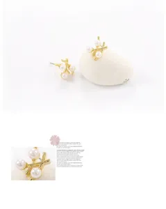 Gros plan de boucles d'oreilles branche dorée avec trois perles sur une base minimaliste