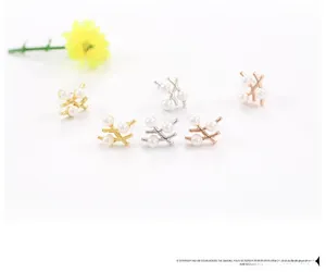 Trois couleurs de boucles d'oreilles branche coréennes avec perles blanches sur fond blanc