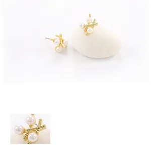 Boucles d'oreilles élégantes en perles croisées dorées sur pierres, style minimaliste