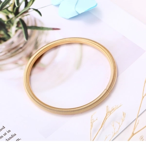 Bracelet minimaliste en acier inoxydable à spirale dorée sur fond de magazine