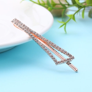 Elegant geometric hair clip in rose gold with shimmering white crystals on a white plate