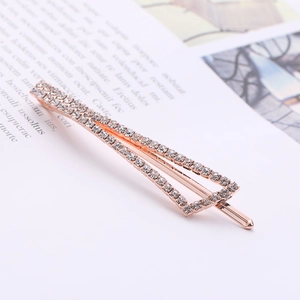Elegant rose gold triangle hair clip with sparkling white crystals on magazine background