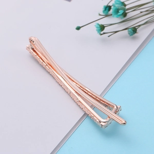 Elegant rose gold metal hair clip with crystal inlay on a minimalist background