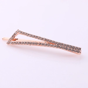 Detailed close-up of a rose gold triangular hair clip with white crystals on pink background