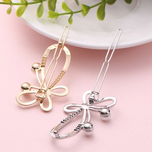 Elegant gold and silver butterfly hair clips with pearls on a decorative tray