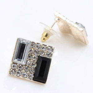 Detail view of square gold earrings featuring black and clear crystals with small diamonds