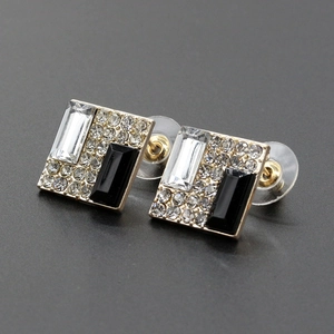 Macro detail of square geometric stud earrings with black and clear stones in gold
