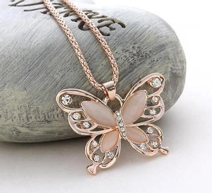 Detailopname van roségouden vlinder hanger met opaalstenen en kleine glanzende strass