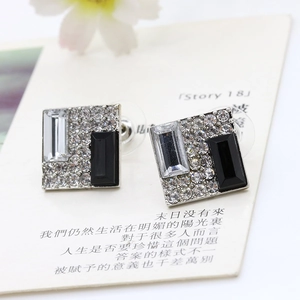 Close-up of geometric square earrings featuring sparkling crystals and black stones