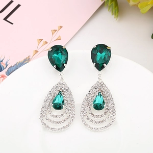 Boucles d'oreilles élégantes goutte d'émeraude et zircons blancs sur plat décoratif