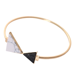 Vista dettagliata del bracciale rigido dorato con inserti in pietra marmorea triangolare