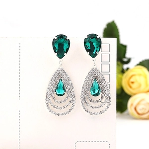 Gros plan sur des boucles d'oreilles émeraude en forme de poire avec monture en argent poli