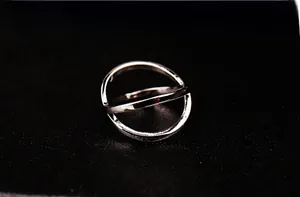 Macro shot of silver geometric ring with crossbar on textured black surface