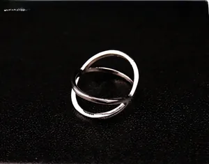 Detailed close-up of a silver crisscross geometric open ring with polished metal finish