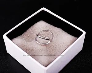 Detail view of silver hollow geometric cross ring in a white jewelry gift box