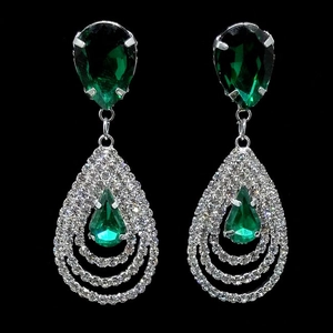 Détail de boucles d'oreilles argentées avec pierres vertes et cadres en pavé de cristal