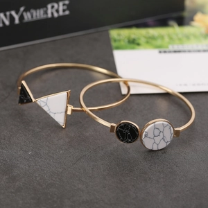 Dettaglio di bracciali aperti dorati con pietre marmoree geometriche bianche e nere