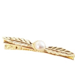 Barrette à cheveux plume dorée élégante avec perle blanche sur un fond blanc épuré