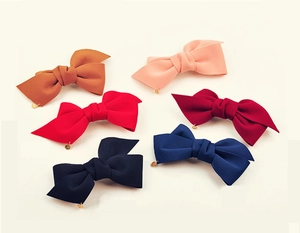 Détail de plusieurs barrettes à nœuds en tissu avec d'élégants pendentifs en métal doré