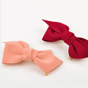 Gros plan détaillé de barrettes à nœuds en tissu rouge foncé et rose avec breloques dorées