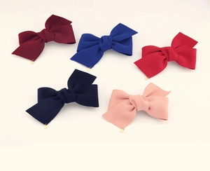 Détails de cinq barrettes nœuds en tissu de couleurs variées avec pendentifs dorés