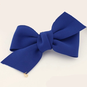 Vue détaillée d'une pince à cheveux nœud en tissu bleu marine avec un petit pendentif doré