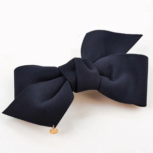 Détail d'une pince à cheveux avec nœud en tissu côtelé bleu foncé et pendentif doré rond