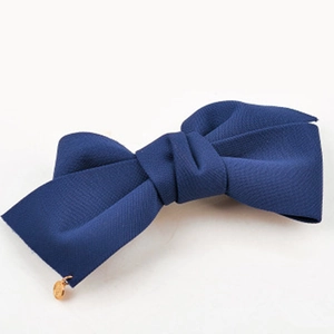 Vue détaillée d'un nœud papillon en tissu bleu marine avec breloque dorée pour cheveux